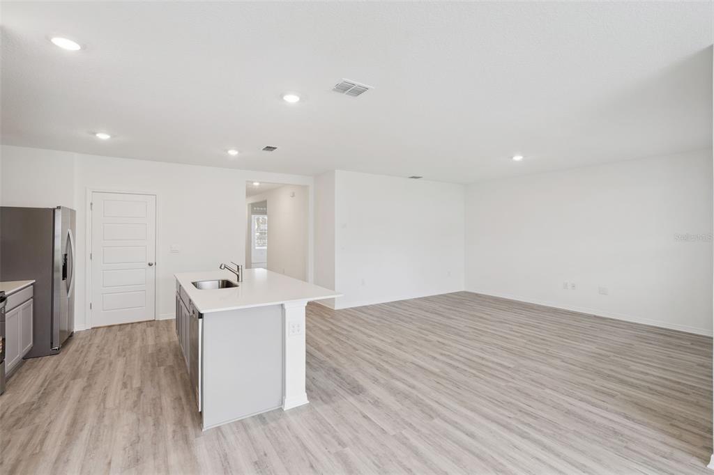 A kitchen with a white island and stainless steel refrigerator opens into a living area — 4254 LESTER DRIVE, LAKE WALES, FL
