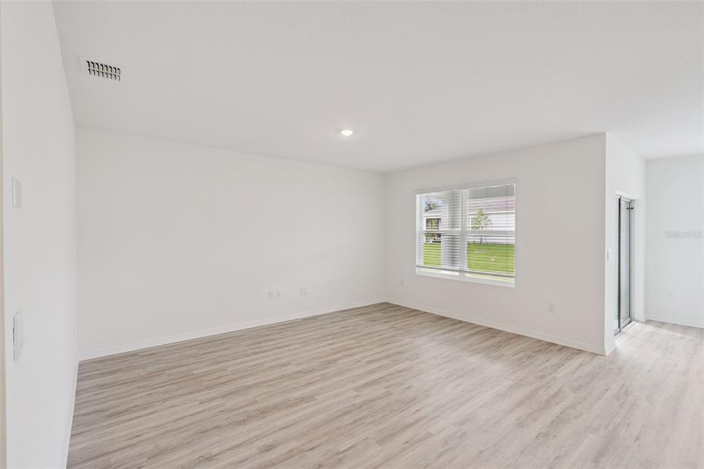 An empty room with white walls, light wood-look flooring, a window, and a sliding door — 4254 LESTER DRIVE, LAKE WALES, FL