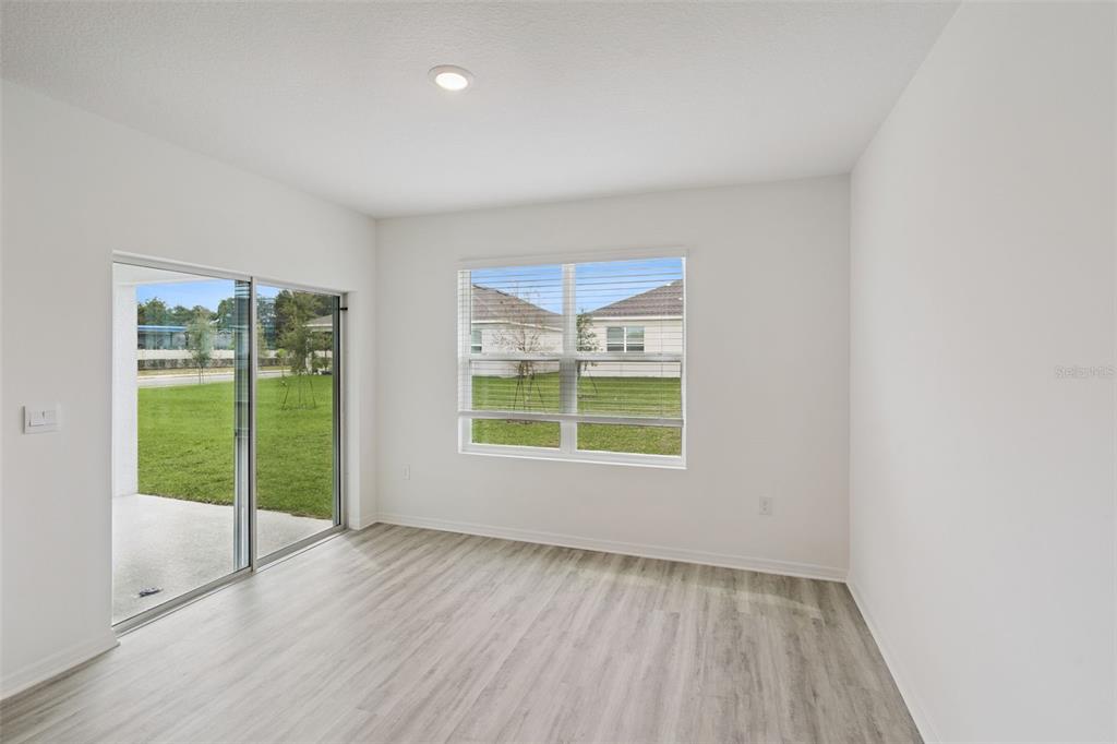 A bright room with light wood-look flooring, a sliding glass door, and a large window — 4254 LESTER DRIVE, LAKE WALES, FL