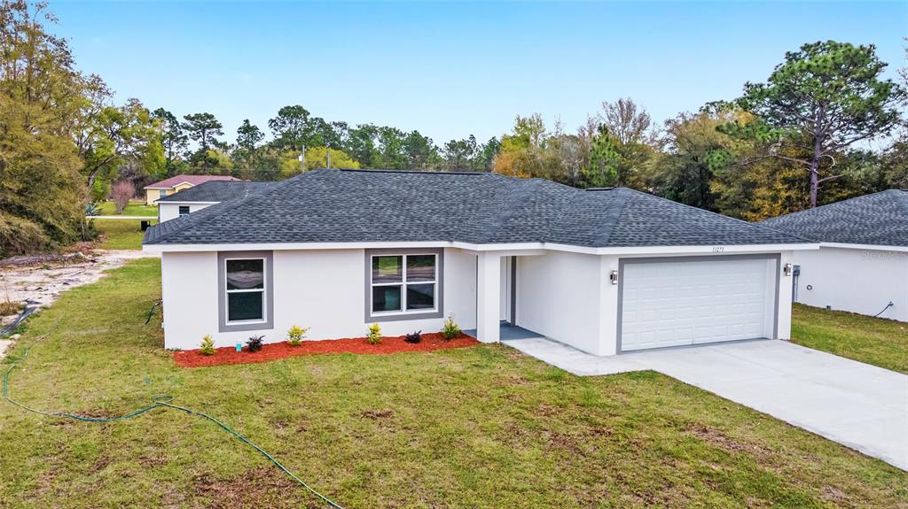 A single-story white house with a gray roof and a two-car garage — 13740 SW 113TH LANE, DUNNELLON, FL