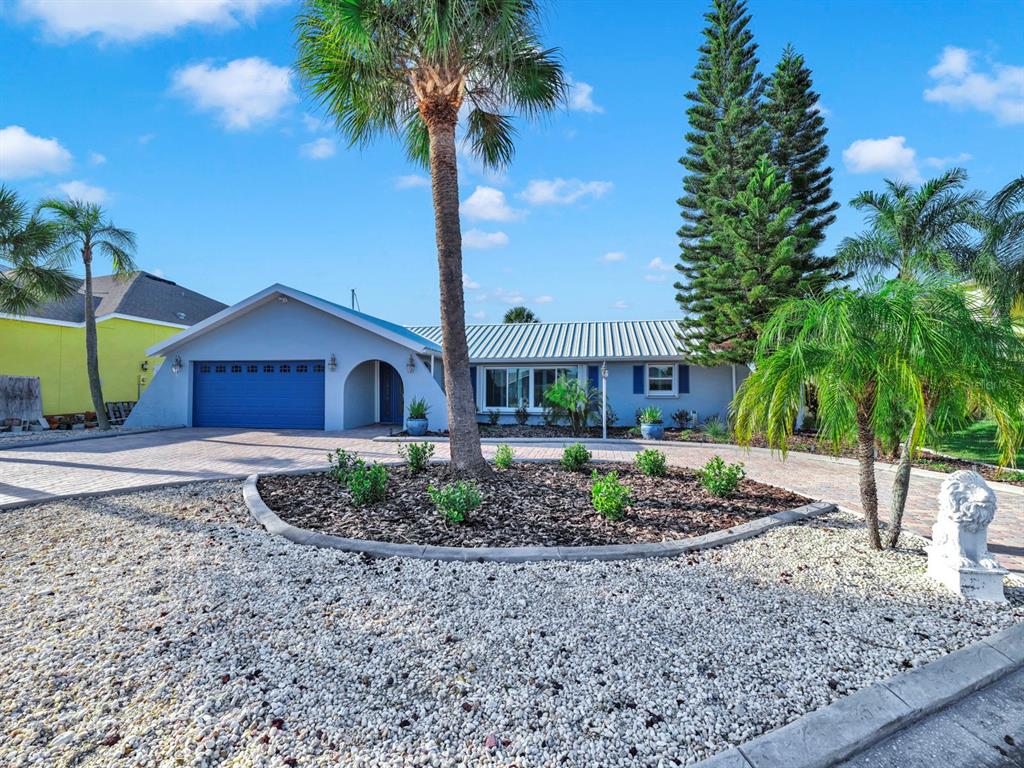 A single-story house with a blue garage, palm trees, and a circular landscaped front yard — 6344 COTTONWOOD LANE, APOLLO BEACH, FL