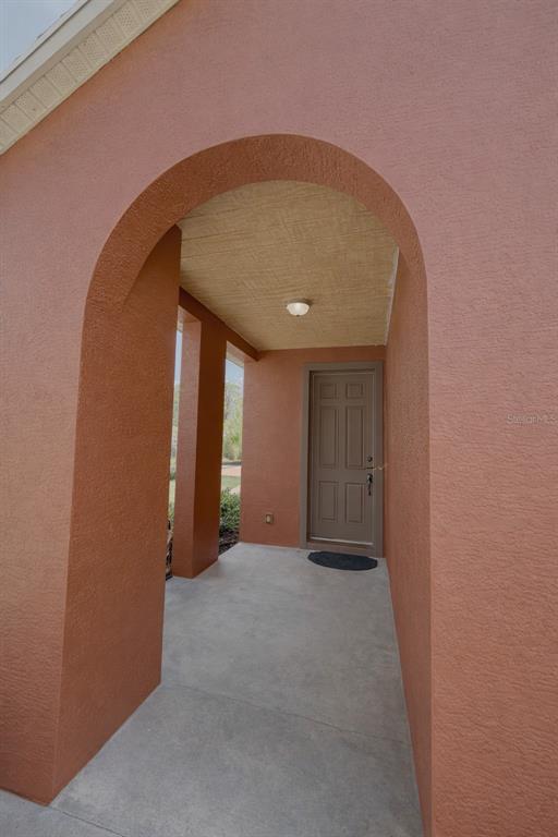 A covered entryway features a stucco archway, a concrete porch, and a brown front door — 549 WHITE PLAINS AVENUE SW, PALM BAY, FL