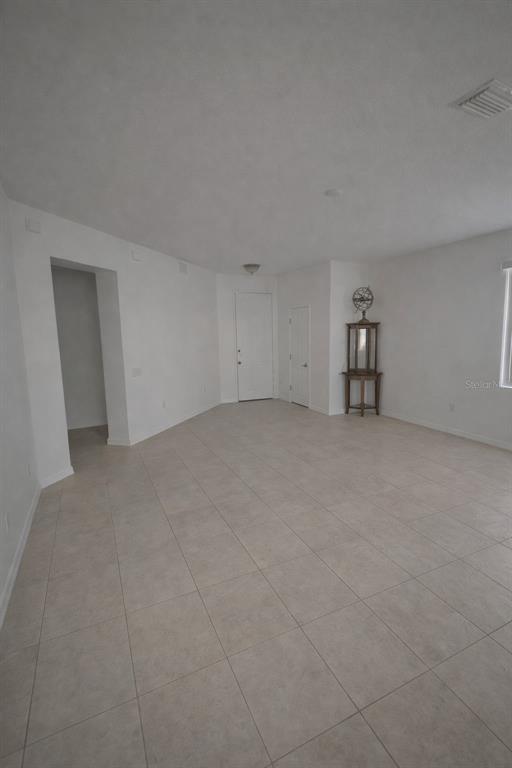 A spacious, empty room features white walls, light-colored tile flooring, and a corner display cabinet — 549 WHITE PLAINS AVENUE SW, PALM BAY, FL