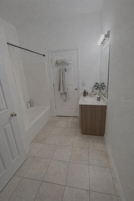 A bathroom features a tiled floor, a white vanity, a mirror, and a shower-tub combination — 549 WHITE PLAINS AVENUE SW, PALM BAY, FL