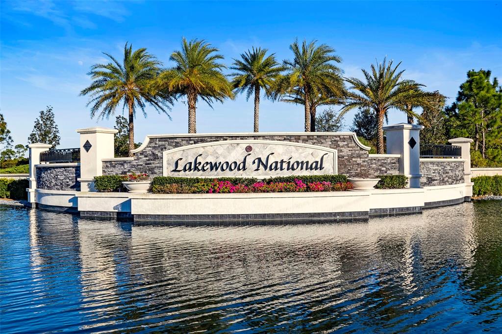 The Lakewood National community entrance sign stands behind a pond with palm trees — 17510 GAWTHROP DRIVE UNIT 204, BRADENTON, FL
