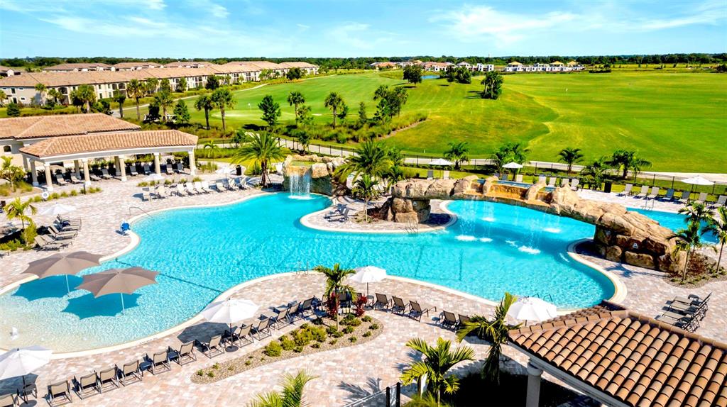 An aerial view of a resort-style swimming pool with rock features and a golf course — 17510 GAWTHROP DRIVE UNIT 204, BRADENTON, FL