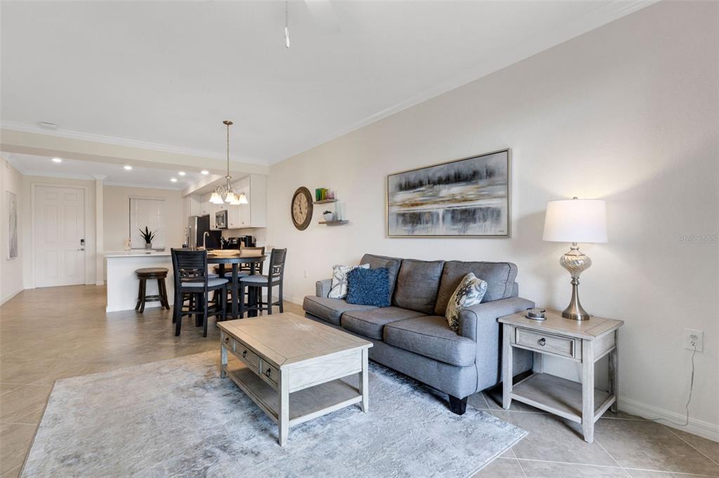 A living room with a grey sofa, coffee table, and an adjacent dining area — 17510 GAWTHROP DRIVE UNIT 204, BRADENTON, FL