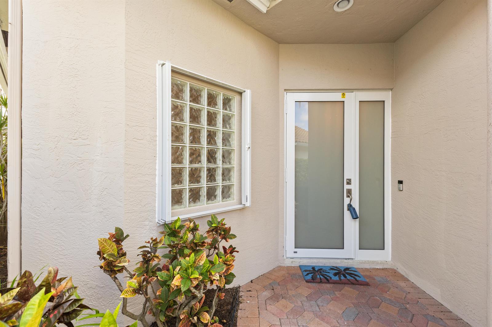 A front entryway features a glass block window, a frosted glass door, and paver flooring — 1009 Diamond Head Way, Palm Beach Gardens FL 33418, PALM BEACH GARDENS, FL