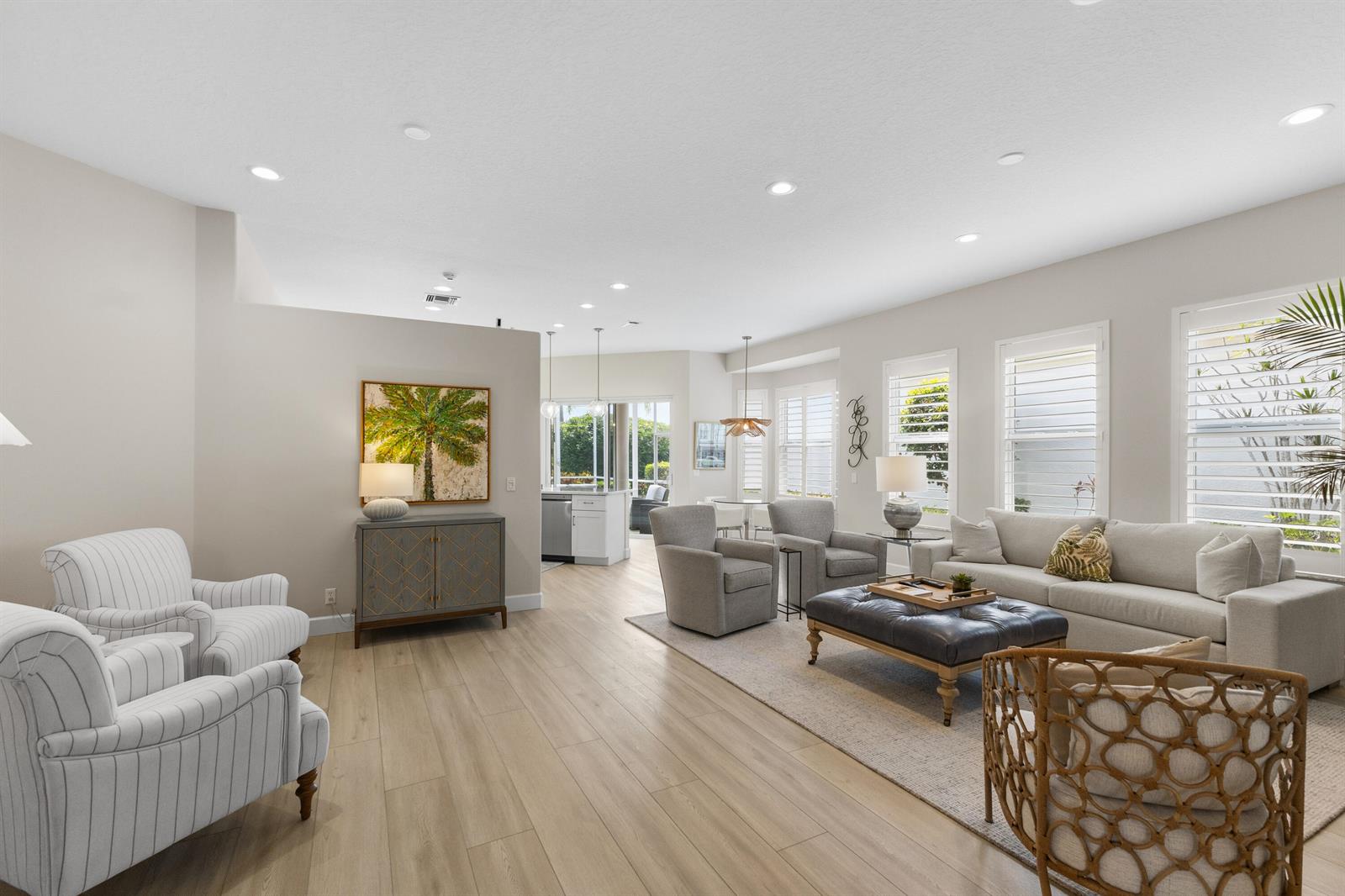 A spacious living room features light wood flooring, neutral walls, and a large sectional sofa — 1009 Diamond Head Way, Palm Beach Gardens FL 33418, PALM BEACH GARDENS, FL