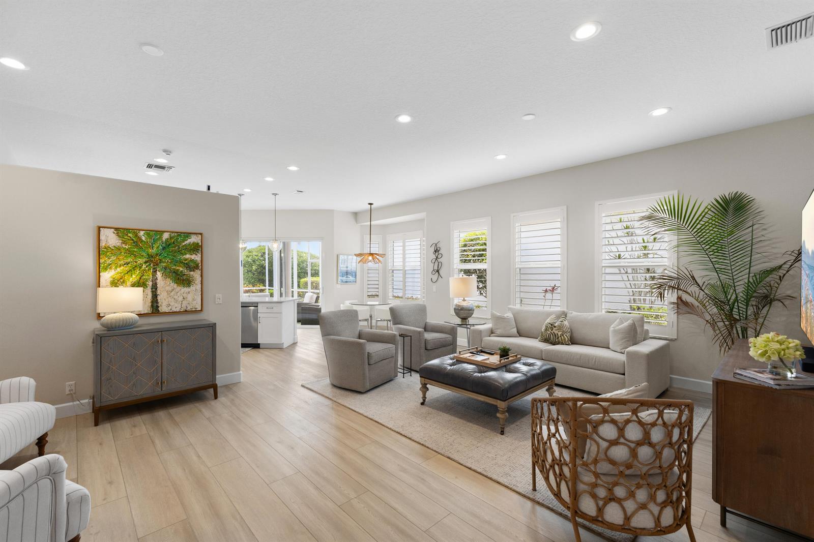 A bright living room features light wood floors, a neutral sofa, and a large palm painting — 1009 Diamond Head Way, Palm Beach Gardens FL 33418, PALM BEACH GARDENS, FL