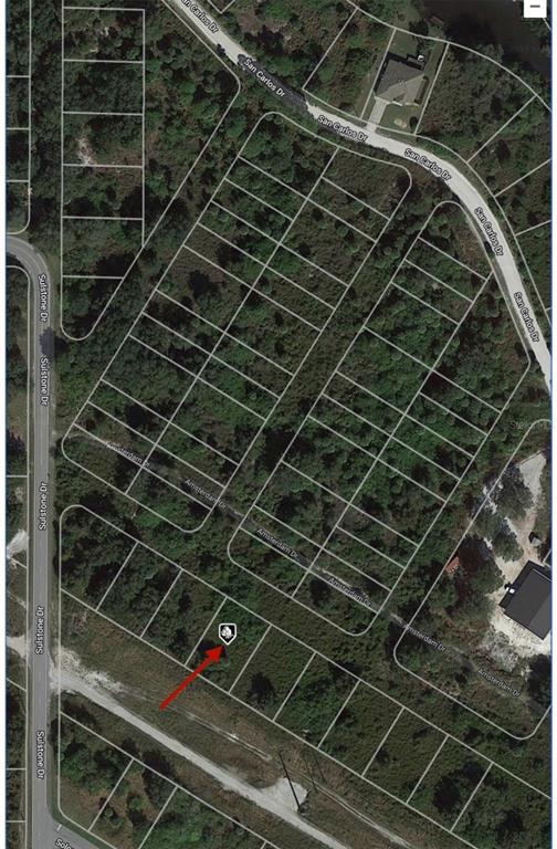 This is an aerial map showing a vacant residential lot highlighted with a red arrow — 27065 AMSTERDAM DRIVE, PUNTA GORDA, FL