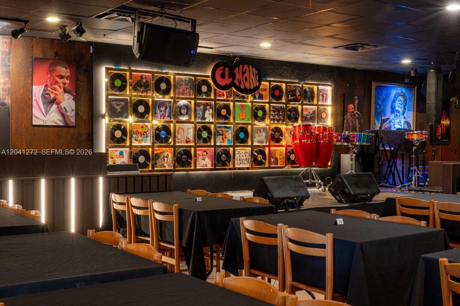 A restaurant interior features a wall display of vinyl records, stage equipment, and dining tables — 1200 NW 78 Avenue, Miami FL 33126, MIAMI, FL