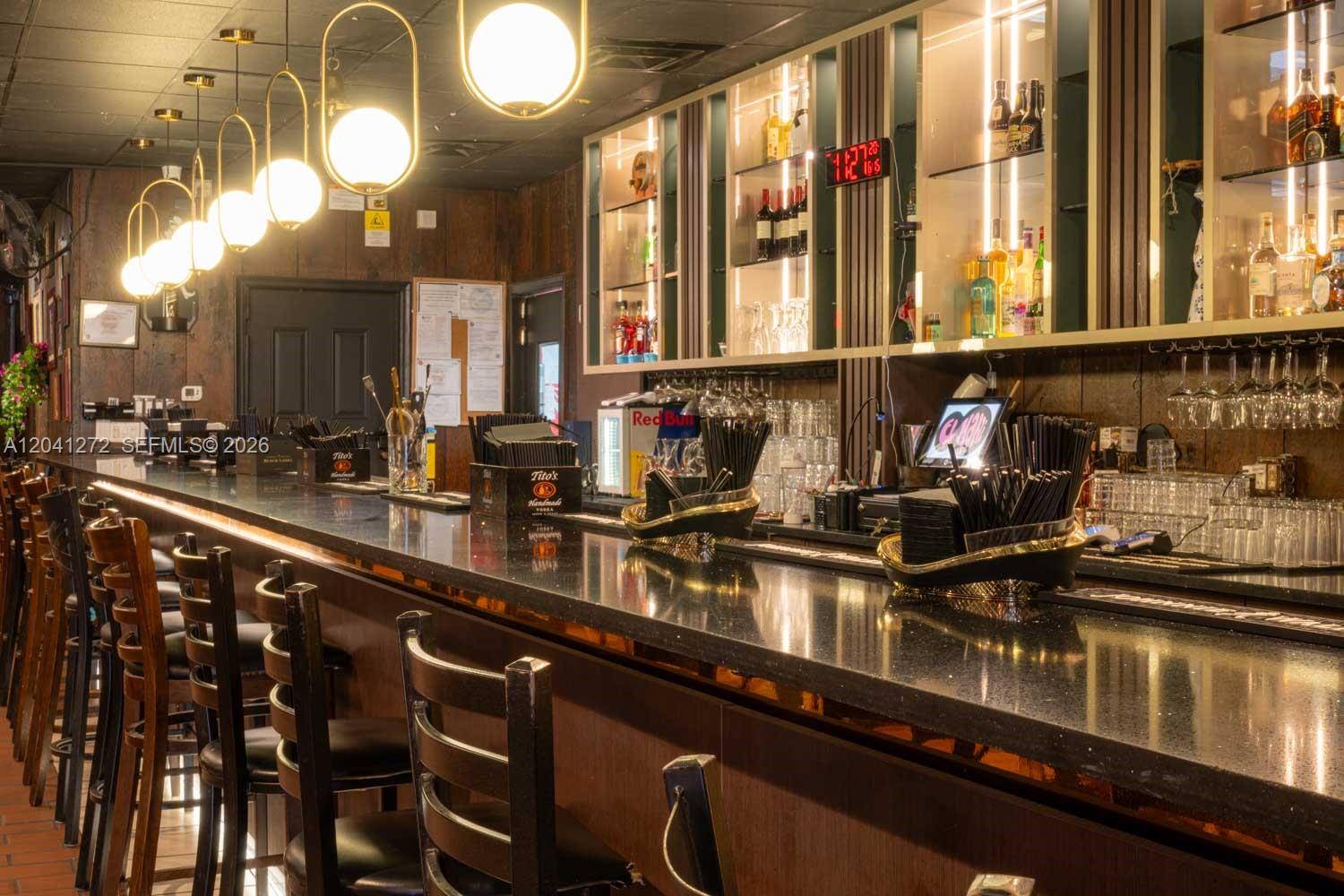A bar interior features a long black countertop, dark wood paneling, and modern pendant lighting — 1200 NW 78 Avenue, Miami FL 33126, MIAMI, FL