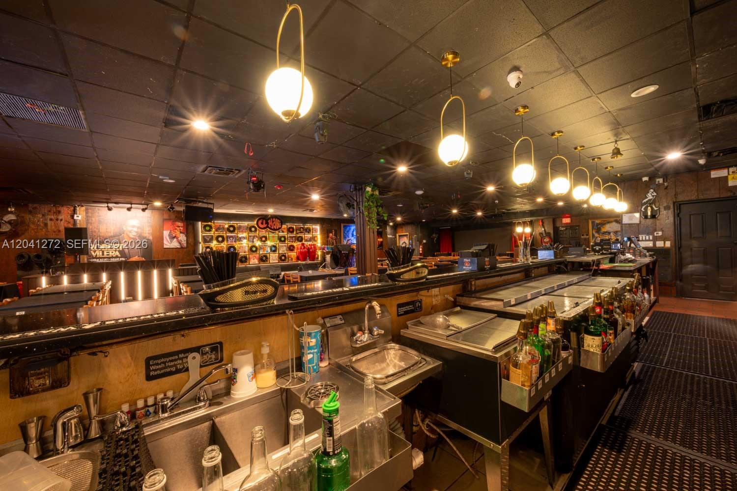 A bar interior features a long service counter, stainless steel sinks, and hanging globe lights — 1200 NW 78 Avenue, Miami FL 33126, MIAMI, FL