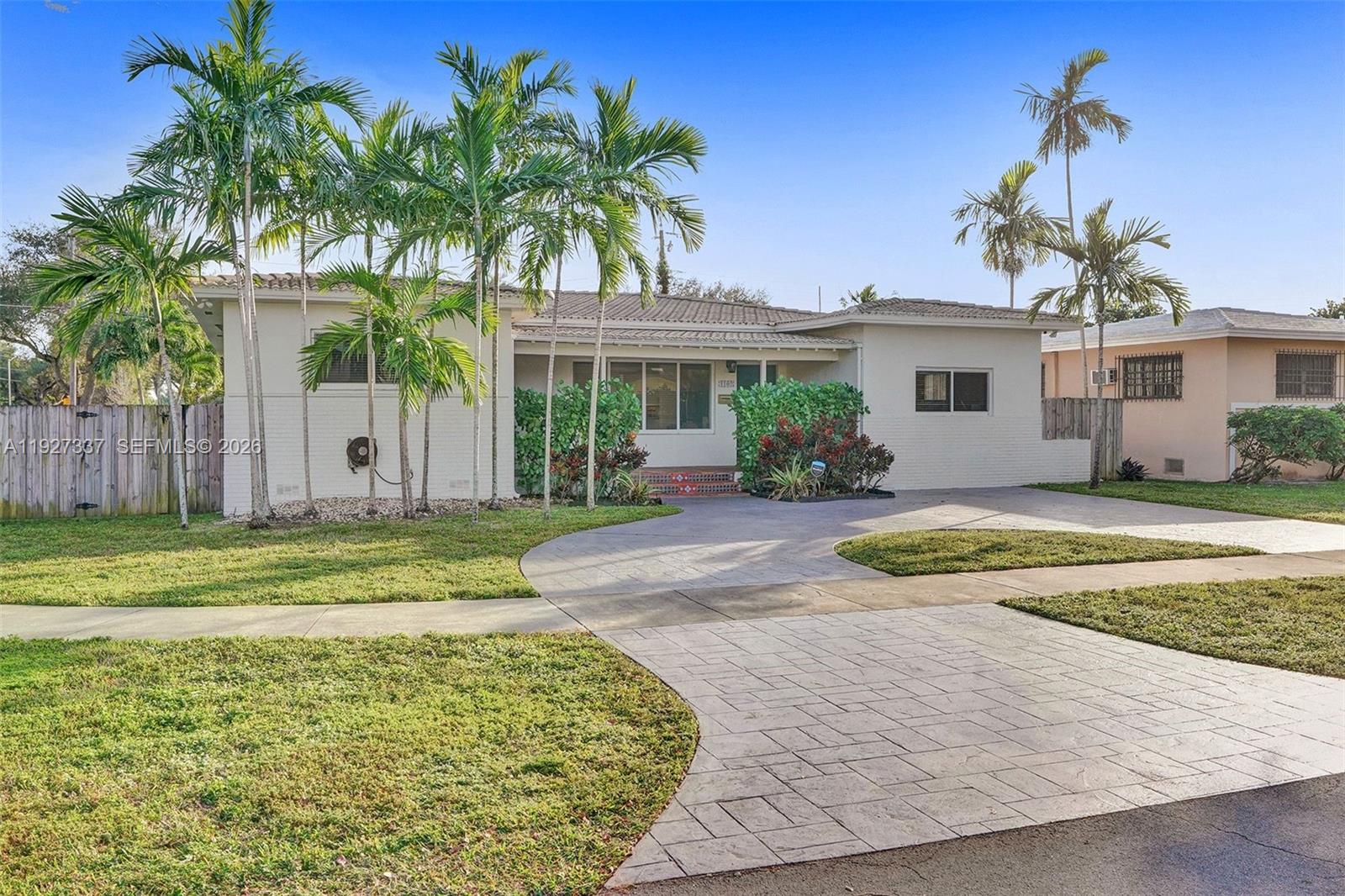 A single-story white house with a paved driveway and palm trees in the front yard — 1102 Meadowlark Ave, Miami Springs FL 33166, MIAMI SPRINGS, FL