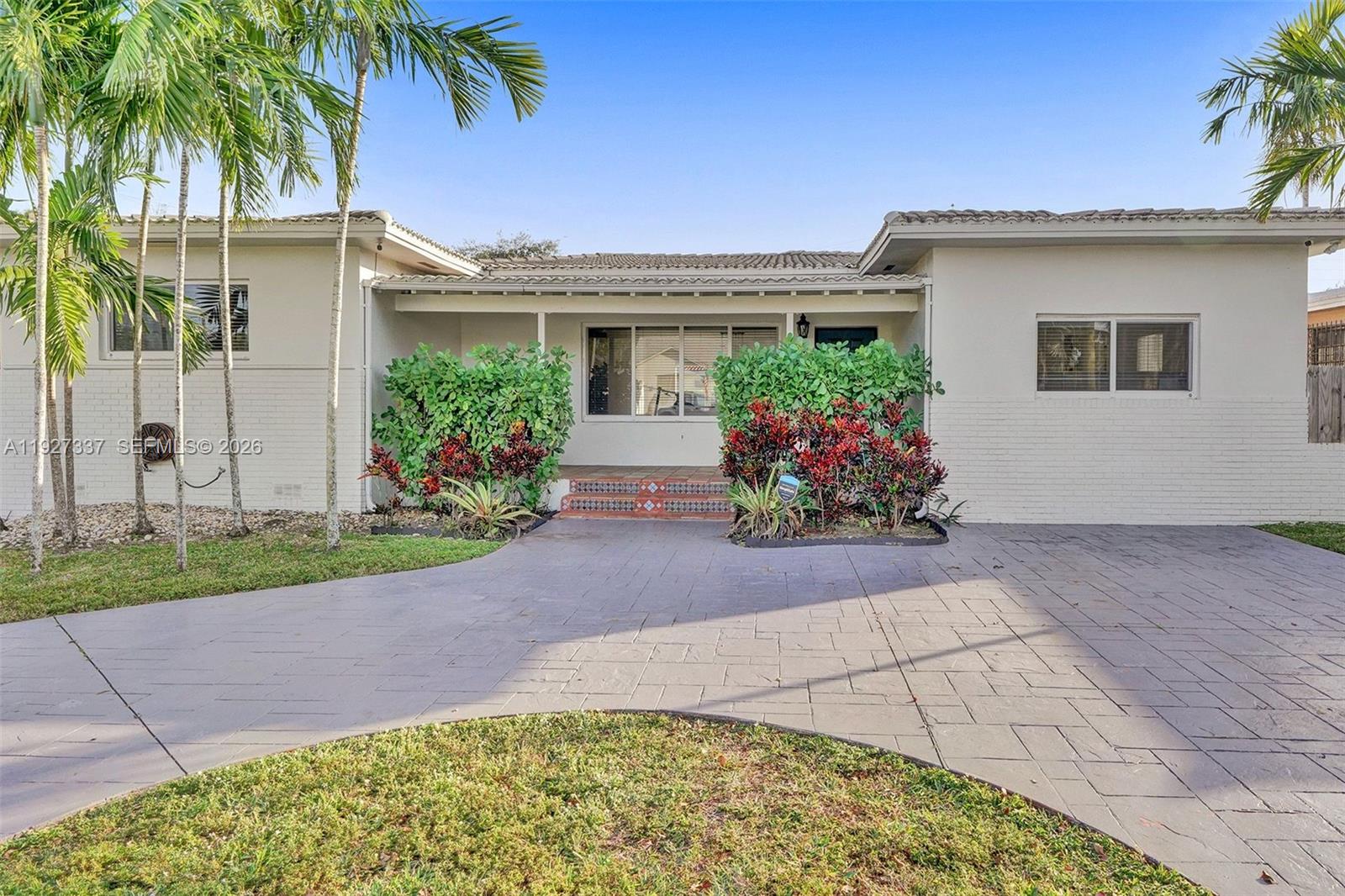 A single-story house with a white brick exterior, a tiled driveway, and palm trees — 1102 Meadowlark Ave, Miami Springs FL 33166, MIAMI SPRINGS, FL
