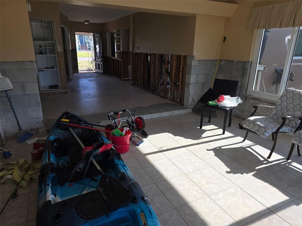 An unfinished room with exposed wall studs, tile flooring, a kayak, and a doorway — 12200 4TH STREET E, TREASURE ISLAND, FL
