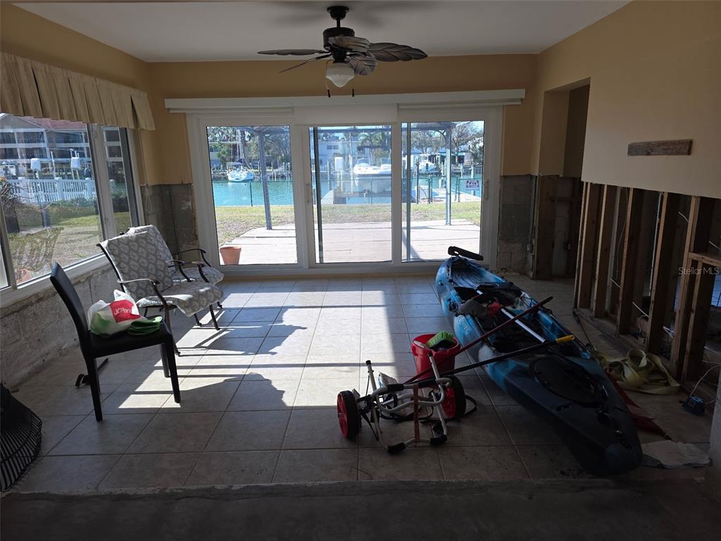 A sunroom with tile flooring, a ceiling fan, and sliding glass doors overlooking a canal — 12200 4TH STREET E, TREASURE ISLAND, FL