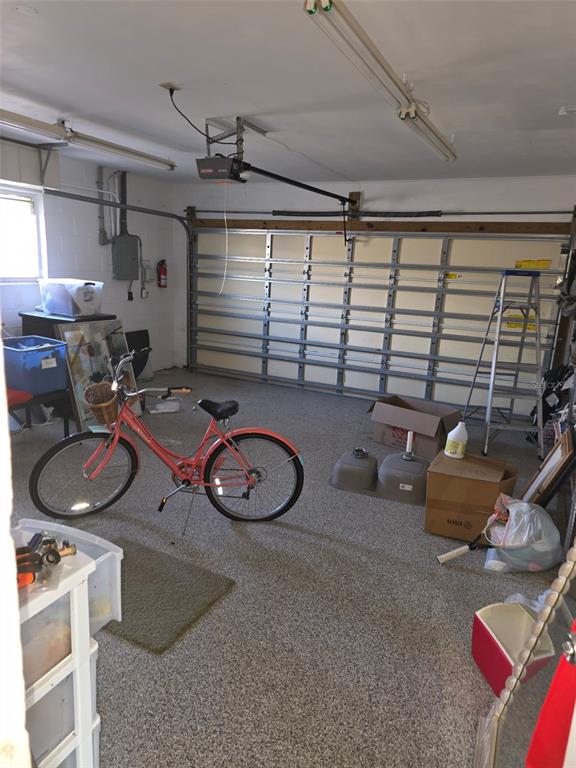 A garage with a speckled floor, a coral bicycle, a ladder, and a double sink basin — 12200 4TH STREET E, TREASURE ISLAND, FL