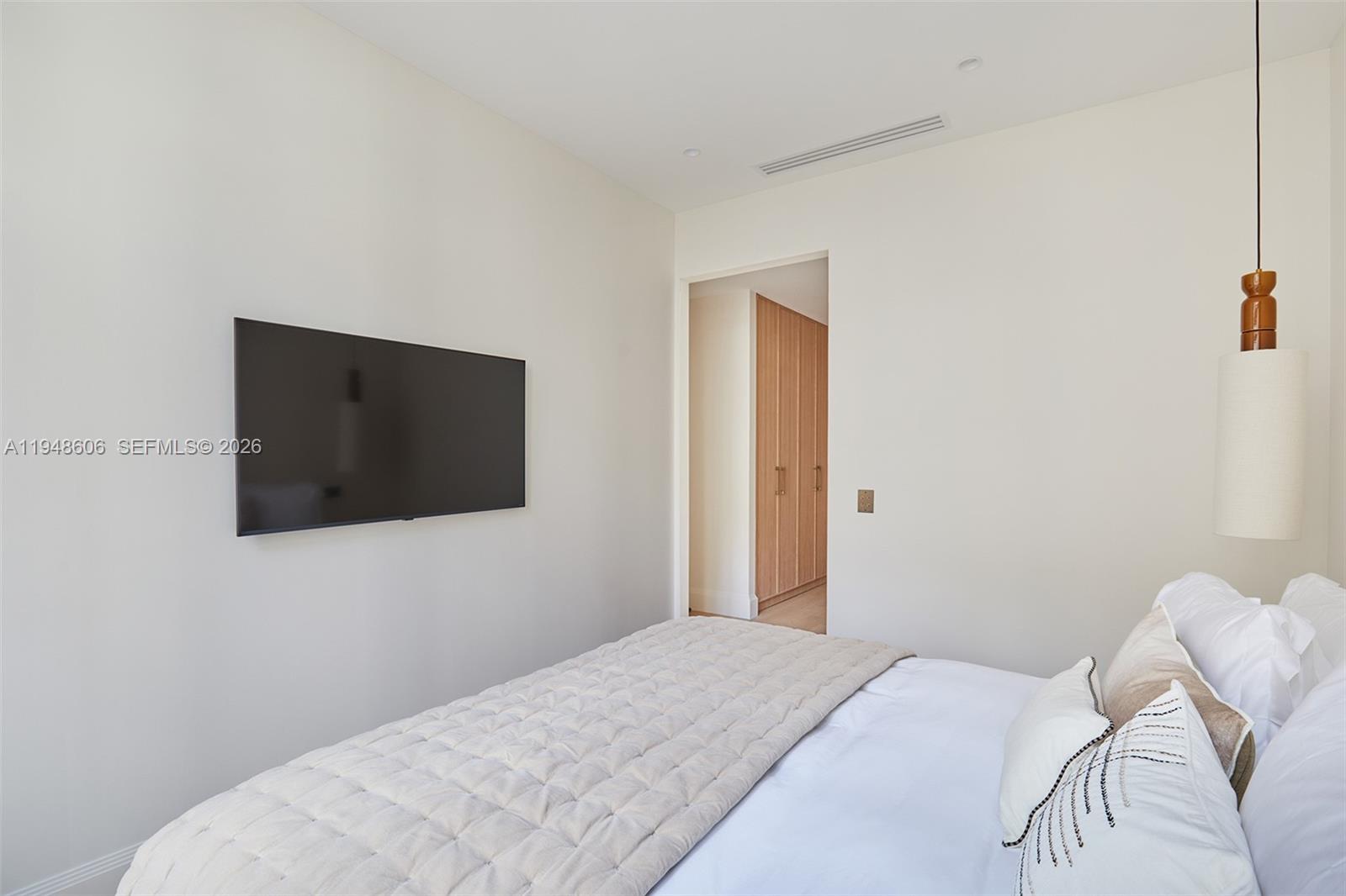 A bedroom features a wall-mounted television, a bed with white bedding, and a pendant light — 9 Avenue Frederic Le Play # 401, Fr, Fr