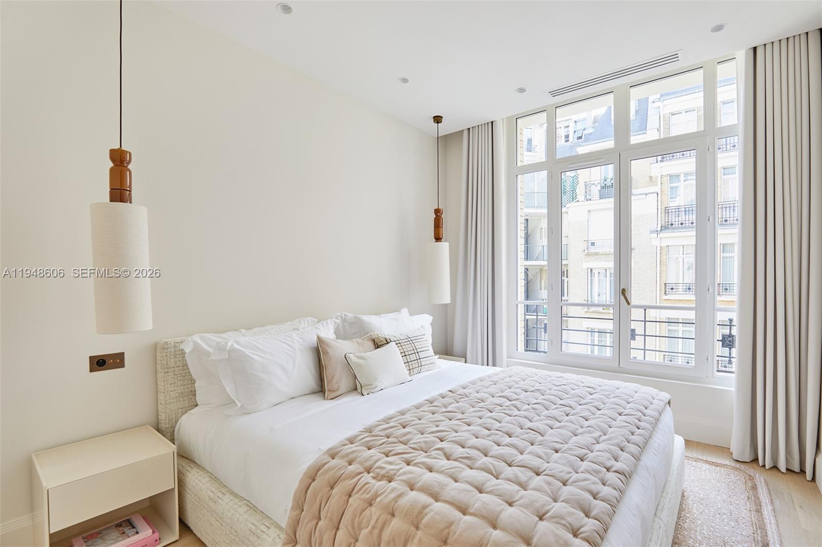 A modern bedroom features a quilted bed, pendant lights, and large windows with city views — 9 Avenue Frederic Le Play # 401, Fr, Fr