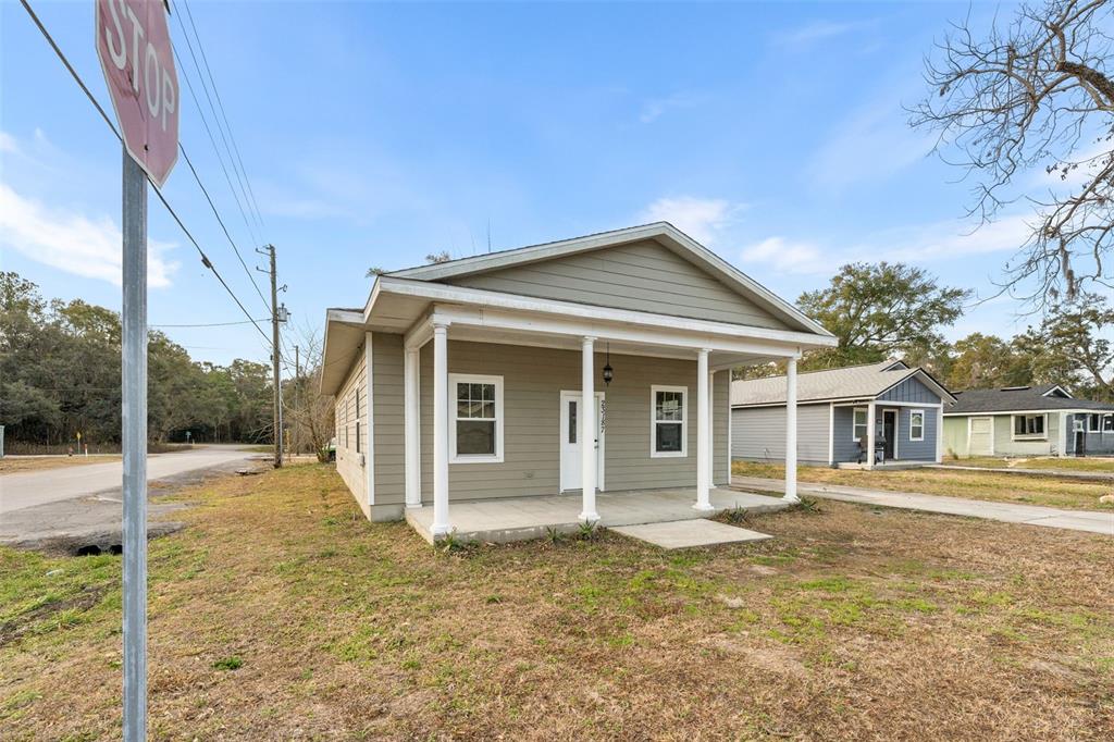 A single-story house with light green siding and a covered front porch stands outdoors — 23187 NW 179 PLACE, HIGH SPRINGS, FL