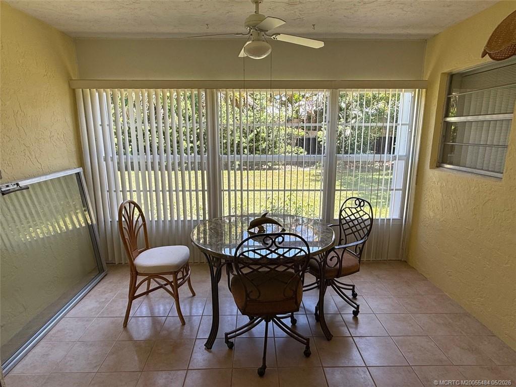 A sunroom features tile flooring, a dining set, and large windows with vertical blinds — 2950 SE Ocean Boulevard # 2, Stuart FL 34996, STUART, FL