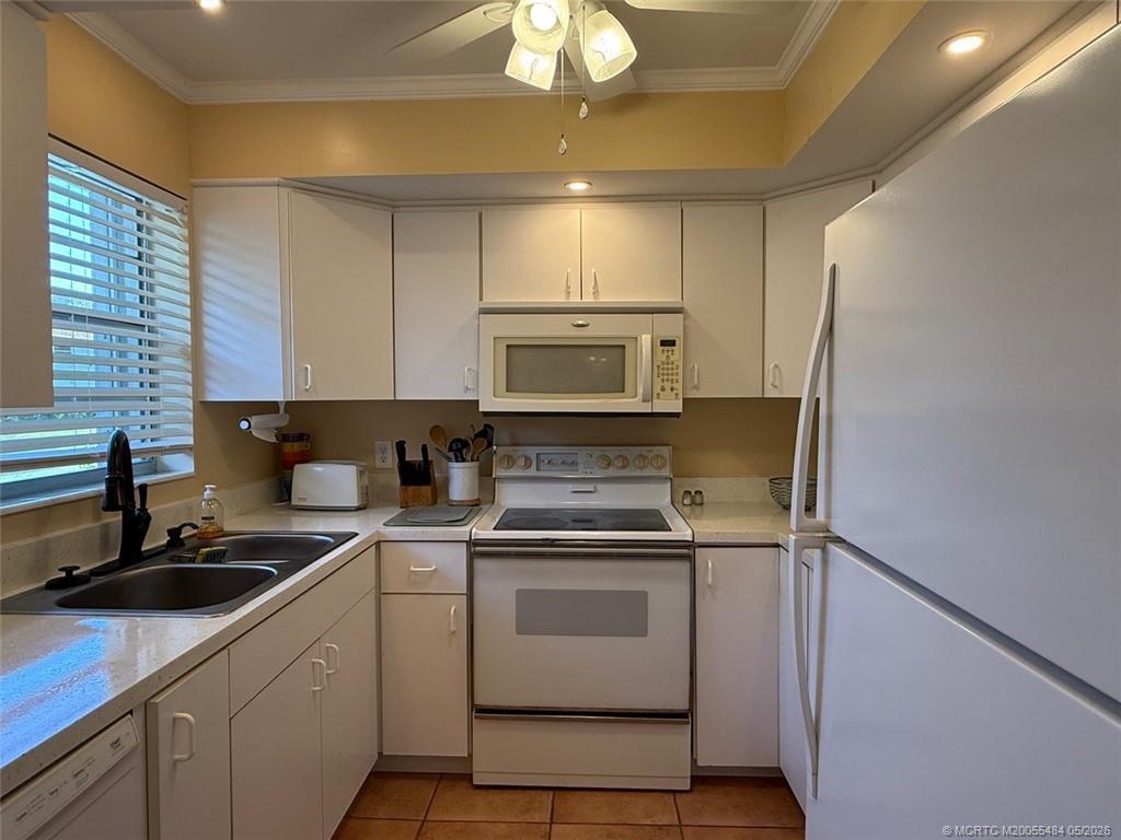A kitchen features white cabinets, white appliances, a double sink, and tile flooring — 2950 SE Ocean Boulevard # 2, Stuart FL 34996, STUART, FL