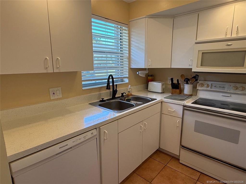 A kitchen features white cabinets, a double sink, a dishwasher, and a white stove — 2950 SE Ocean Boulevard # 2, Stuart FL 34996, STUART, FL