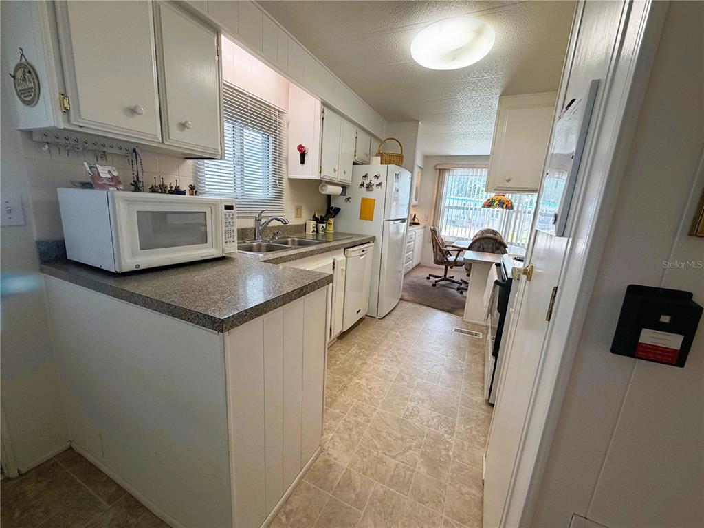 A kitchen features white cabinets, a microwave, a refrigerator, and a window over the sink — 111 CHESTNUT STREET, LEESBURG, FL