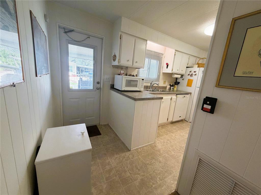 A kitchen with white cabinets, a microwave, and a door leading to the outside — 111 CHESTNUT STREET, LEESBURG, FL
