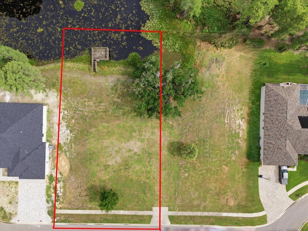 An aerial view shows a vacant residential lot with a small dock on a pond — WOODS END COURT, TAMPA, FL