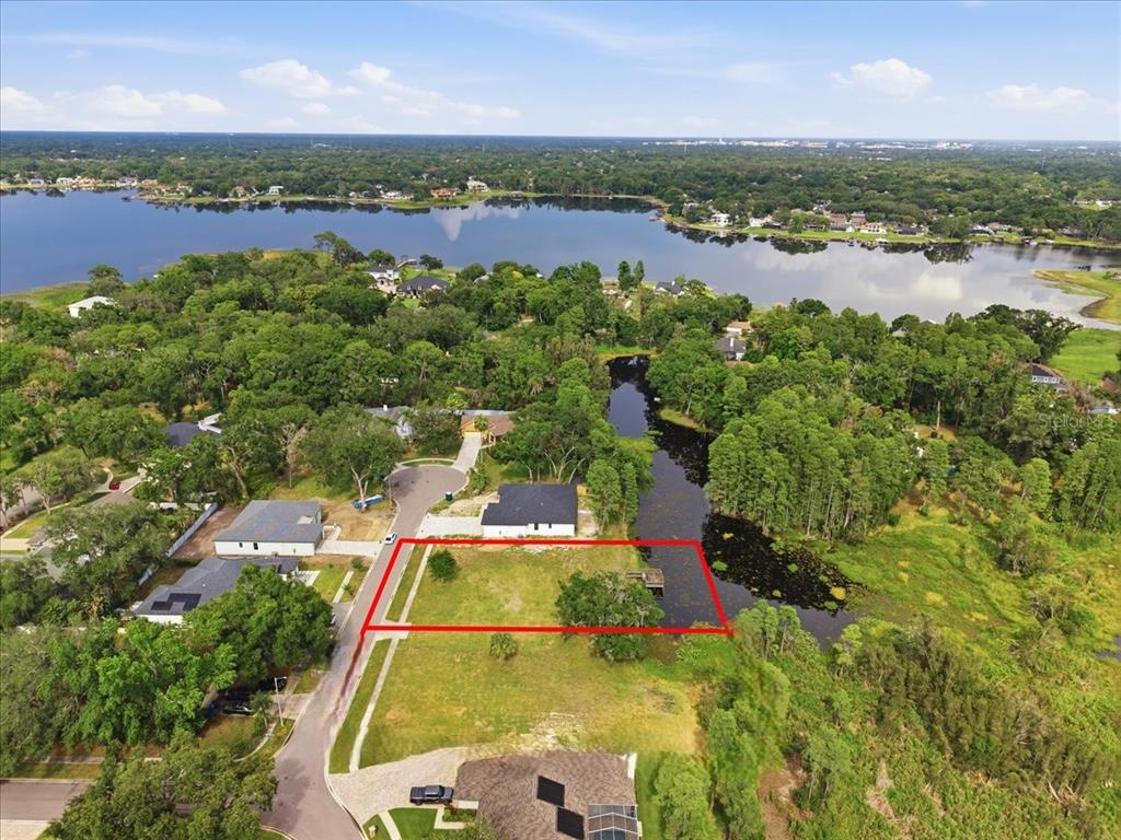 An aerial view shows a vacant rectangular lot outlined in red next to a pond — WOODS END COURT, TAMPA, FL