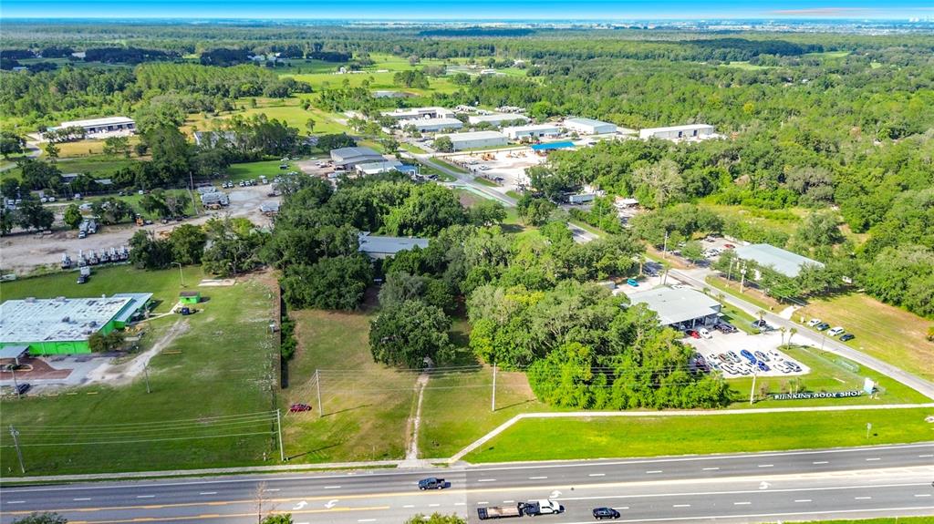 An aerial view shows a commercial property with several buildings and parking lots near a highway — 1450 STATE ROAD 44, LEESBURG, FL