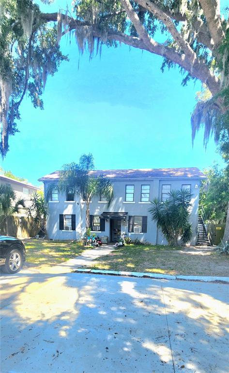A two-story apartment building with a gray exterior, a central entrance, and surrounding trees — 301 SE AVENUE B UNIT 4, WINTER HAVEN, FL