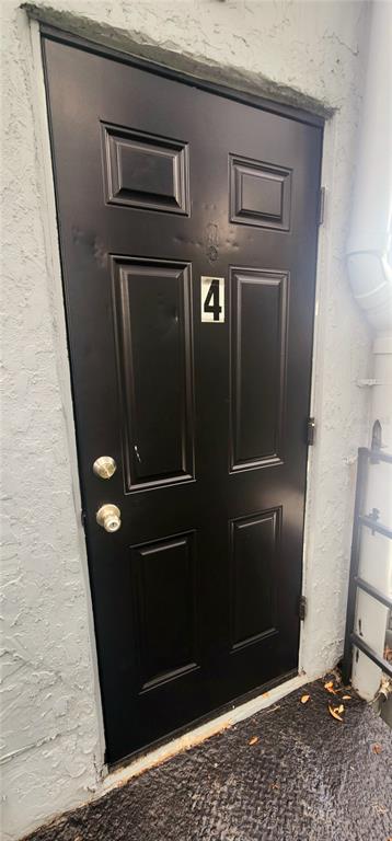 A black six-panel exterior door with the number four mounted on it — 301 SE AVENUE B UNIT 4, WINTER HAVEN, FL