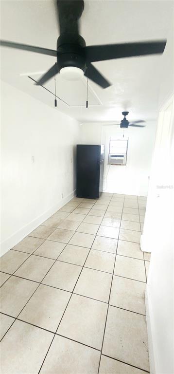 A narrow room with white walls, light-colored floor tiles, two ceiling fans, and a black refrigerator — 301 SE AVENUE B UNIT 4, WINTER HAVEN, FL