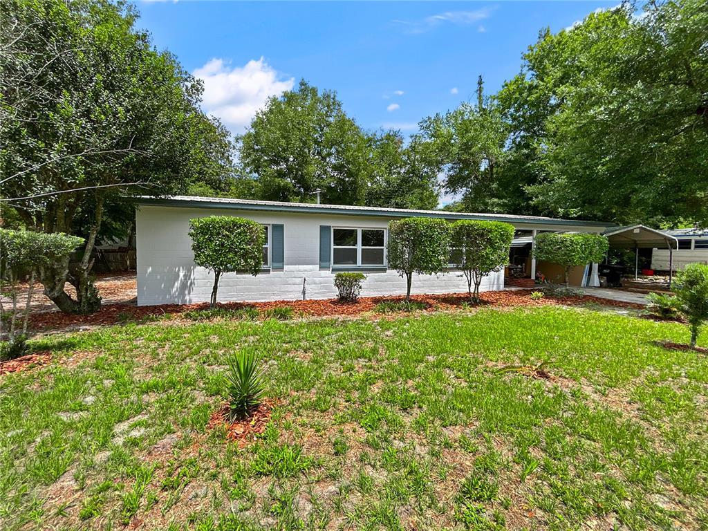 An open-concept living room and kitchen featuring wood-look flooring, a ceiling fan, and neutral decor — 1507 NE 12TH TERRACE, GAINESVILLE, FL