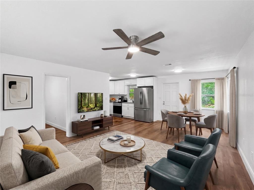 A bedroom features a gray upholstered bed, two windows with white curtains, and a ceiling fan — 1507 NE 12TH TERRACE, GAINESVILLE, FL