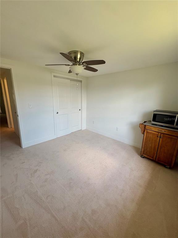 A bedroom features beige carpet, white walls, a ceiling fan, and a wooden cabinet — 4347 RUSTIC DRIVE, NEW PORT RICHEY, FL