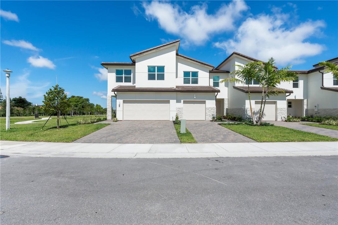 A two-story townhouse with a two-car garage and a paved driveway under a blue sky — 5653 Stradella Drive, Boca Raton FL 33433, BOCA RATON, FL