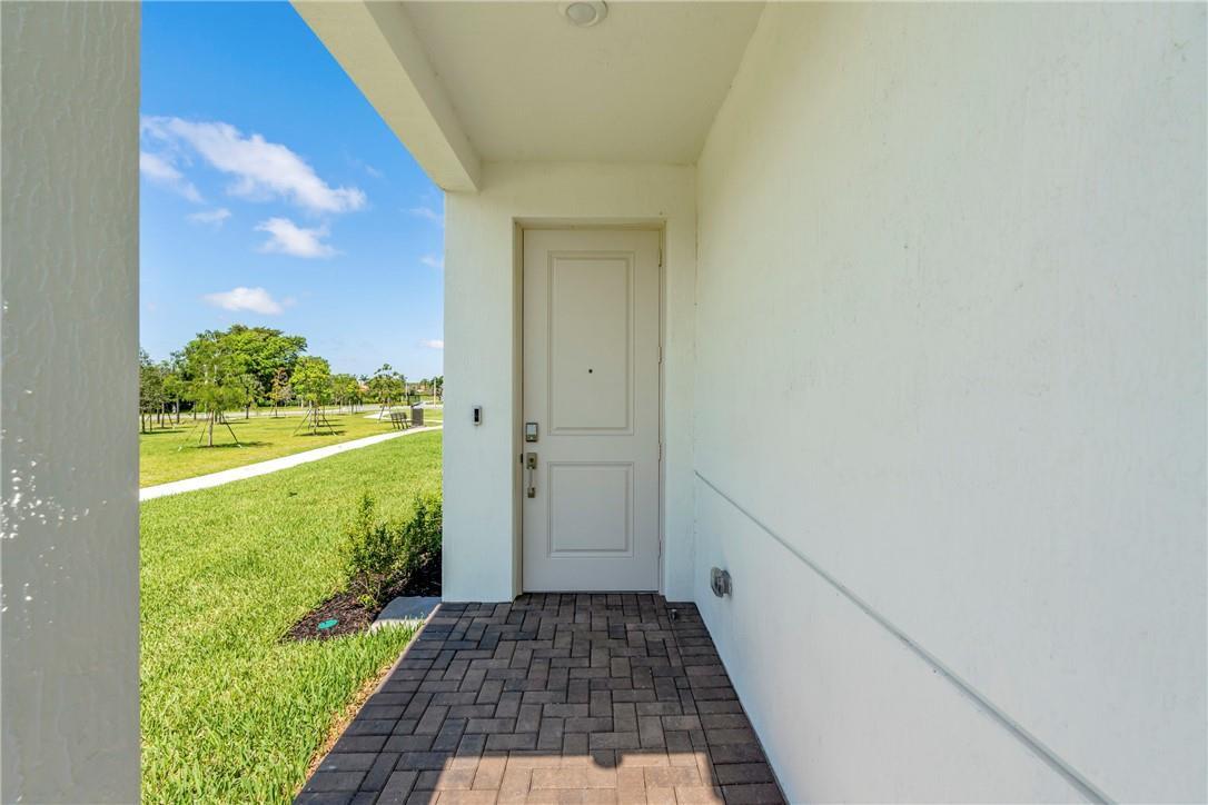 A white front door opens onto a paved entryway overlooking a grassy park area — 5653 Stradella Drive, Boca Raton FL 33433, BOCA RATON, FL