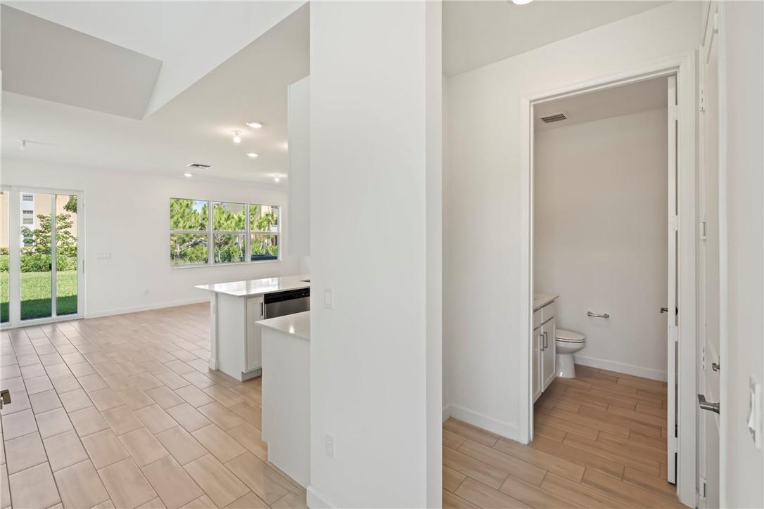 A view from a hallway into a kitchen with an island and an adjacent bathroom — 5653 Stradella Drive, Boca Raton FL 33433, BOCA RATON, FL