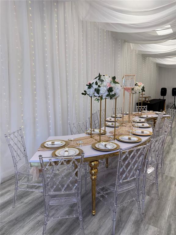 A dining room features a curved table with clear chairs, floral centerpieces, and draped lighting — 1368 NARCOSSEE ROAD, ST CLOUD, FL