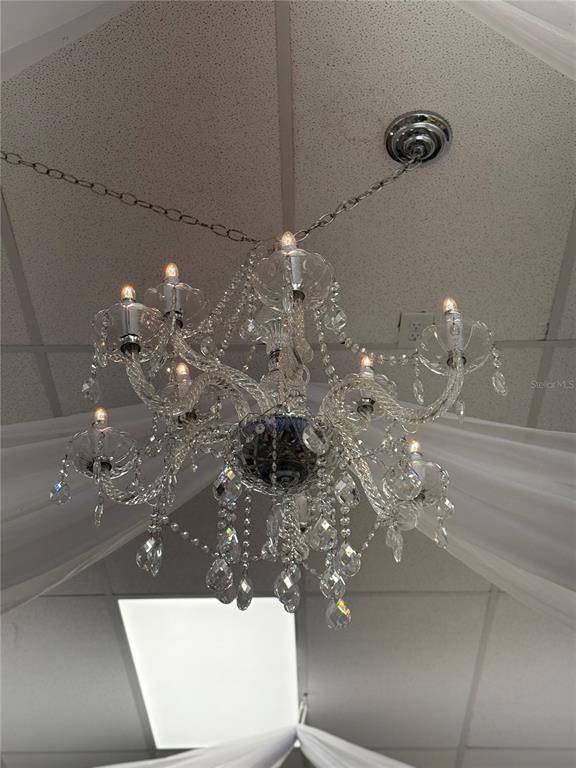 A crystal chandelier hangs from a drop ceiling in a room draped with white fabric — 1368 NARCOSSEE ROAD, ST CLOUD, FL