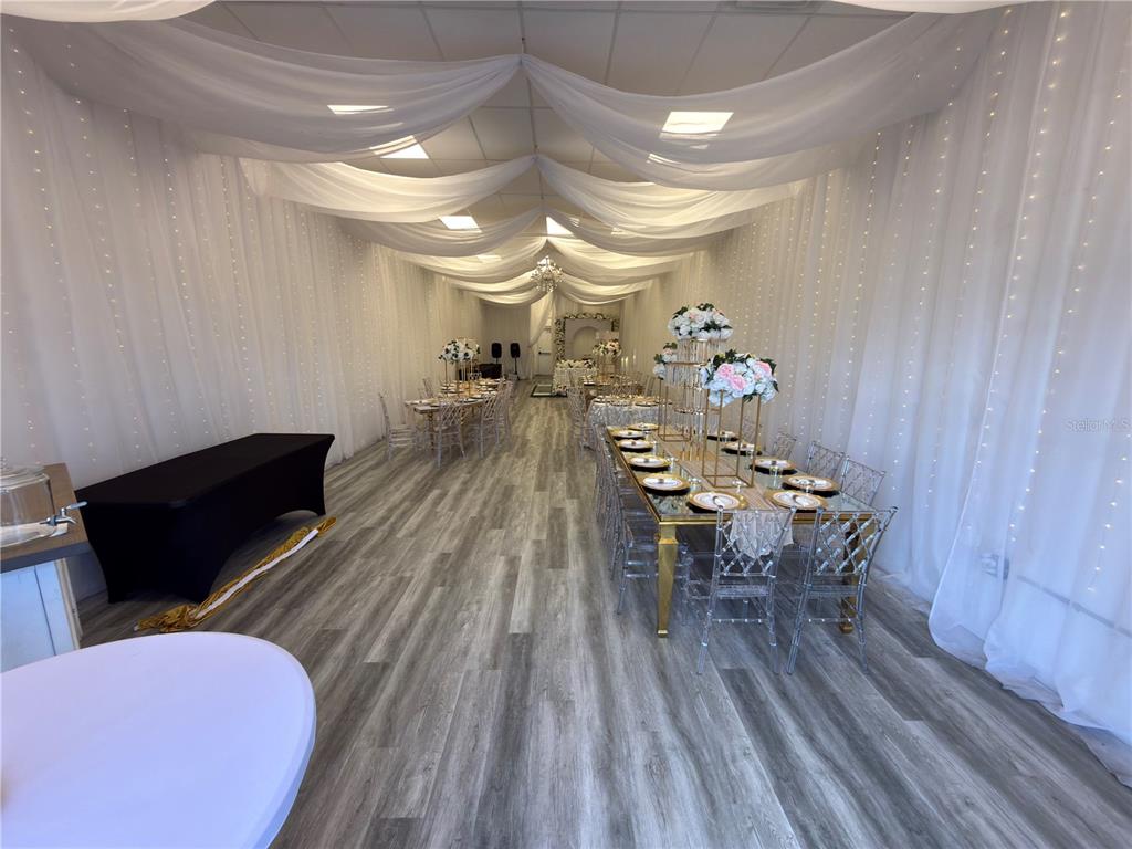 An event space features draped ceilings, fairy lights, and tables set for a formal gathering — 1368 NARCOSSEE ROAD, ST CLOUD, FL