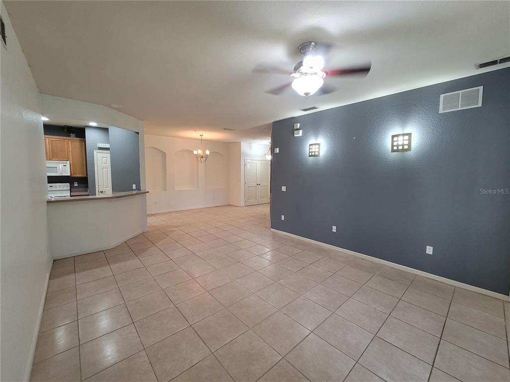 A living room with tile flooring, a ceiling fan, and a dark blue accent wall — 3321 WHITESTONE CIRCLE UNIT 108, KISSIMMEE, FL