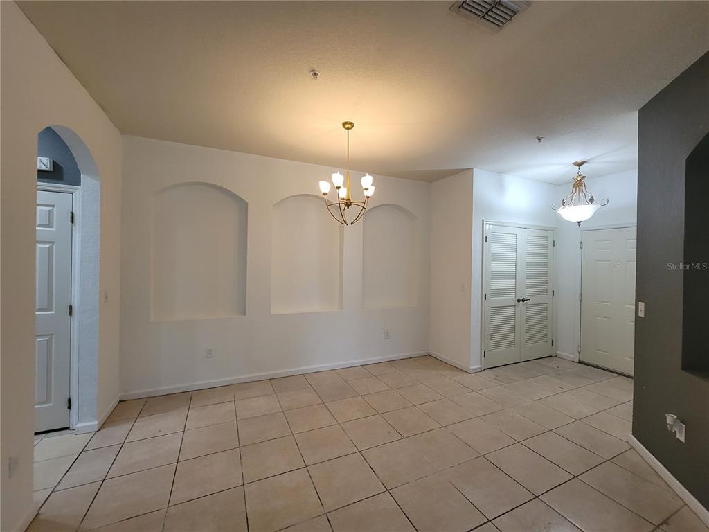 A dining room with tile flooring, three arched wall niches, and two hanging light fixtures — 3321 WHITESTONE CIRCLE UNIT 108, KISSIMMEE, FL