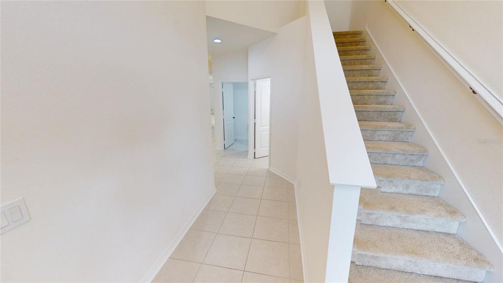 A tiled hallway leads to two doorways with a carpeted staircase on the right — 8331 BAYLISS COURT, ORLANDO, FL