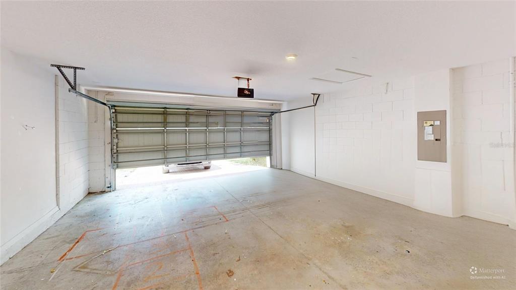 An empty two-car garage with white concrete block walls, a concrete floor, and an open door — 8331 BAYLISS COURT, ORLANDO, FL